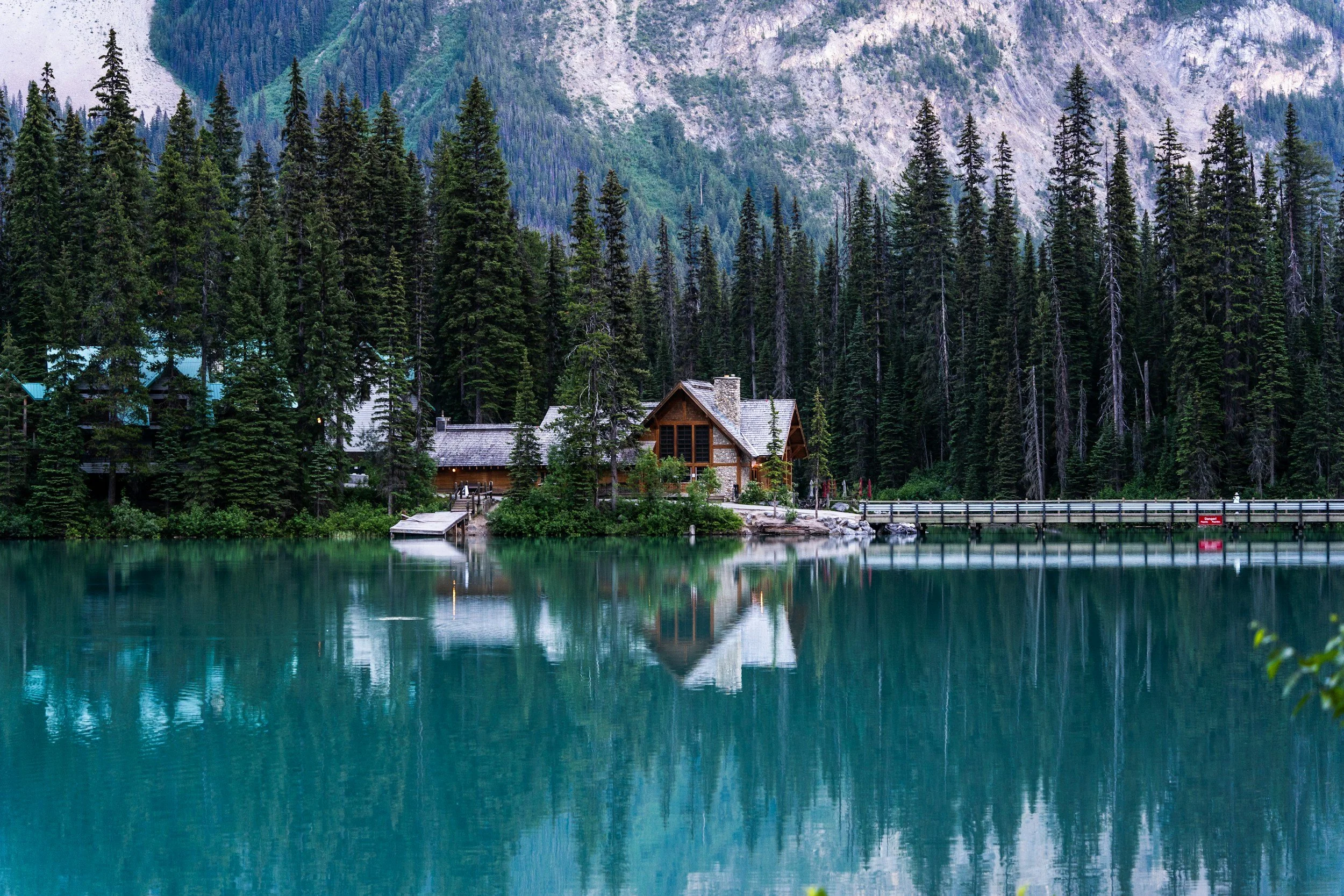 Chalet en bois au bord d’un lac, entouré de forêt